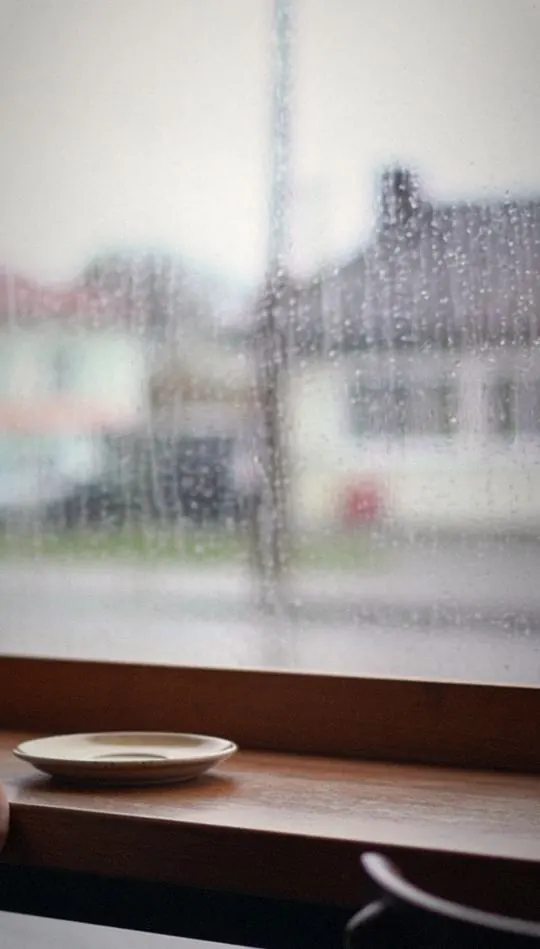 Vertical social ad: customer enjoying coffee by a rainy window